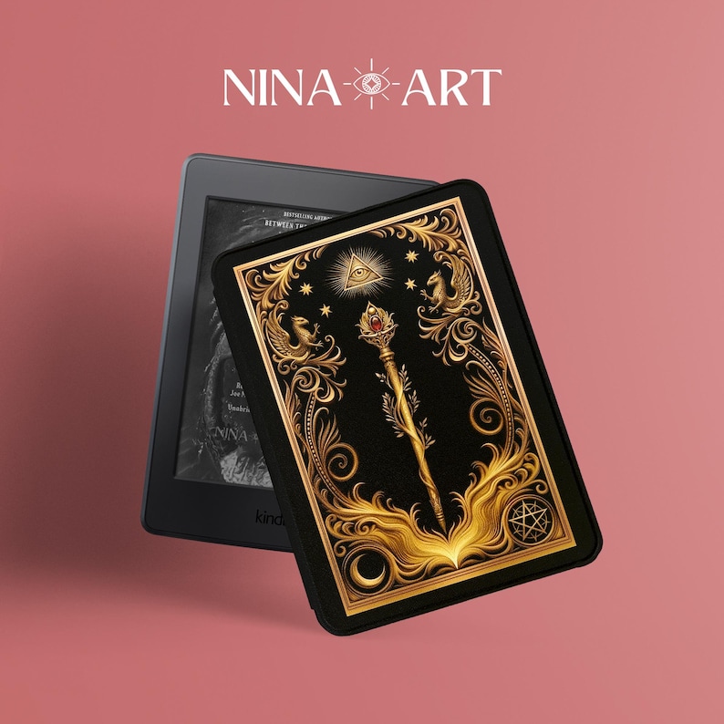 Op de afbeelding: Een zwarte Kindle e-reader met een decoratieve hoes met een goud en zwart sierlijk ontwerp. De hoes heeft een staf met een rode edelsteen, een alziend oog en de tekst "NINA-ART".