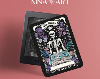 以下が含まれることがあります： 黒色のKindle電子書籍リーダーカバー。骸骨が本を読んでいる様子が描かれており、骸骨の周りは花と星で囲まれています。骸骨の上には「The Reader」という文字があります。
