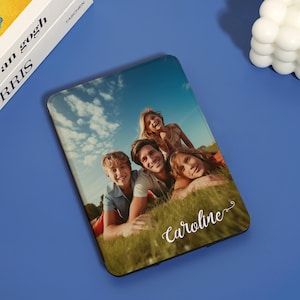 May include: A personalized phone case with a photo of a family of four smiling and lying on the grass. The name "Caroline" is written in cursive on the bottom of the case.