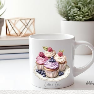 May include: White ceramic coffee mug with a design of four cupcakes with pink, purple, and white frosting topped with raspberries and blueberries. The mug has the text "Coffee Lover" printed on the bottom.