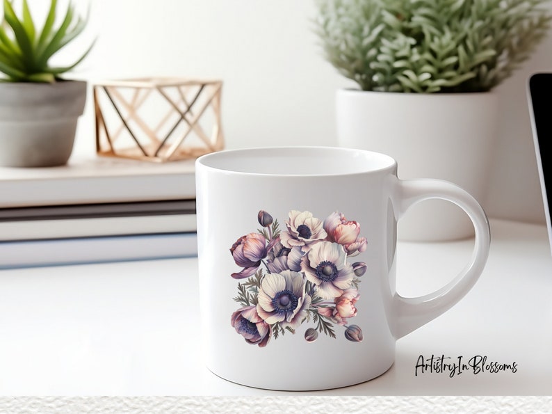 Pu&ograve; includere: Tazza in ceramica bianca con un design floreale che presenta un bouquet di anemoni viola, rosa e bianchi. La tazza ha un manico nero e il testo "Artistry In Blossoms" &egrave; stampato sul fondo.