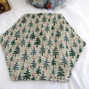 May include: A hexagonal beige placemat with a repeating pattern of green Christmas trees and red stars.
