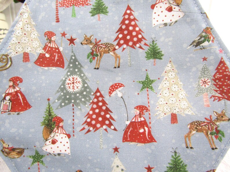 May include: A blue fabric with a repeating pattern of Christmas trees, deer, and people wearing red hats and coats. The trees are decorated with red and white polka dots, snowflakes, and stars. The fabric is perfect for crafting projects like quilts, pillows, and bags.