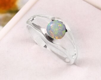 Puede incluir: Un anillo de plata con una piedra de ópalo redonda engastada en una banda sencilla.