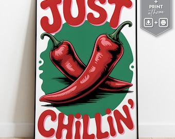 May include: A framed art print with two red chilli peppers on a green circle, with the words "JUST CHILLIN'" in red. The print has a white background and a black frame. The image also includes a small graphic with the words "instant download + print at home".