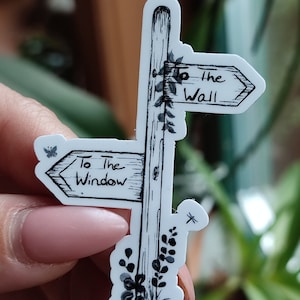 Könnte beinhalten: Schwarz-weiß-Illustration eines hölzernen Wegweisers mit zwei Pfeilen, die in entgegengesetzte Richtungen zeigen. Der linke Pfeil zeigt auf "To the Window" und der rechte Pfeil zeigt auf "To the Wall".