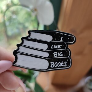 Könnte beinhalten: Schwarzer Aufkleber in Form eines Bücherstapels. Der Aufkleber hat weißen Text mit der Aufschrift "I LIKE BIG BOOKS" mit Sternen. Die Bücher haben weiße Seiten und schwarze Einbände.