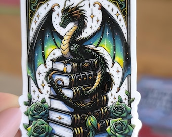 Puede incluir: Una pegatina con un dragón verde con detalles dorados posado sobre una pila de libros. El dragón tiene alas con un patrón de galaxia y está rodeado de estrellas. El texto "THE ROMANTASY BOOK CLUB" está en la parte inferior de la pegatina.