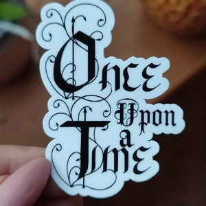 Può includere: Sticker bianco con scritta nera che recita "C'era una volta" in un font stilizzato. Lo sticker ha un bordo decorativo di viti nere.