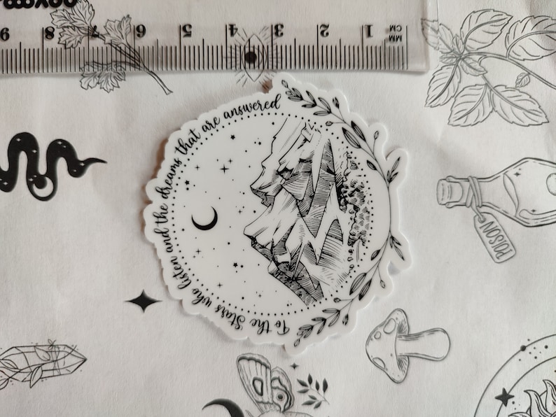 May include: Black and white sticker with a mountain range, crescent moon, and stars. The text reads "To the Stars who listen and the dreams that are answered".