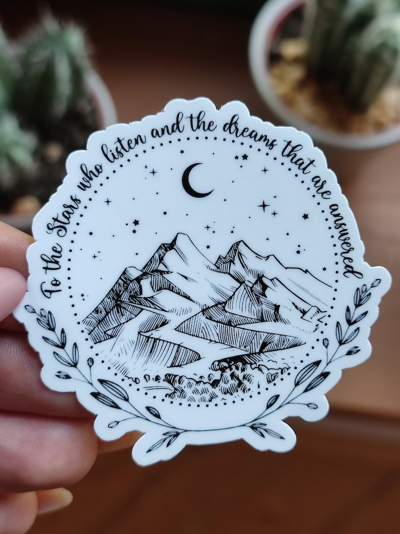 May include: Black and white sticker with a mountain range, crescent moon, and stars. The text reads "To the stars who listen and the dreams that are answered".