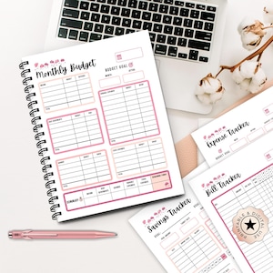 Puede incluir: Un planificador de presupuesto mensual con espiral, con detalles en rosa y la inscripción "Monthly Budget" en la portada. También se ven hojas de seguimiento financiero adicionales para gastos, ahorros y facturas. Un bolígrafo rosa descansa cerca.
