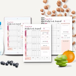 Può includere: Una collezione di diari alimentari giornalieri, tra cui un tablet e un taccuino a spirale, con accenti rosa e la scritta "Daily Food Journal". L'immagine presenta anche un'arancia, una mela verde a fette e mirtilli.
