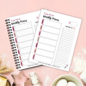 Op de afbeelding: Twee wekelijkse menuplanners met een spiraalbinding, met een roze en wit ontwerp. Elke planner heeft secties voor dagelijkse maaltijden en een boodschappenlijst. De tekst "Weekly Menu" staat bovenaan, met een citaat onderaan: "Cooking is love made visible - one dish at a time."