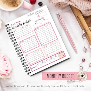 Może przedstawiać: Spiralny miesięczny planer budżetu z różowymi akcentami i napisem "Monthly Budget" na okładce. Planer zawiera sekcje na dochody i wydatki. Obok leży różowy długopis.
