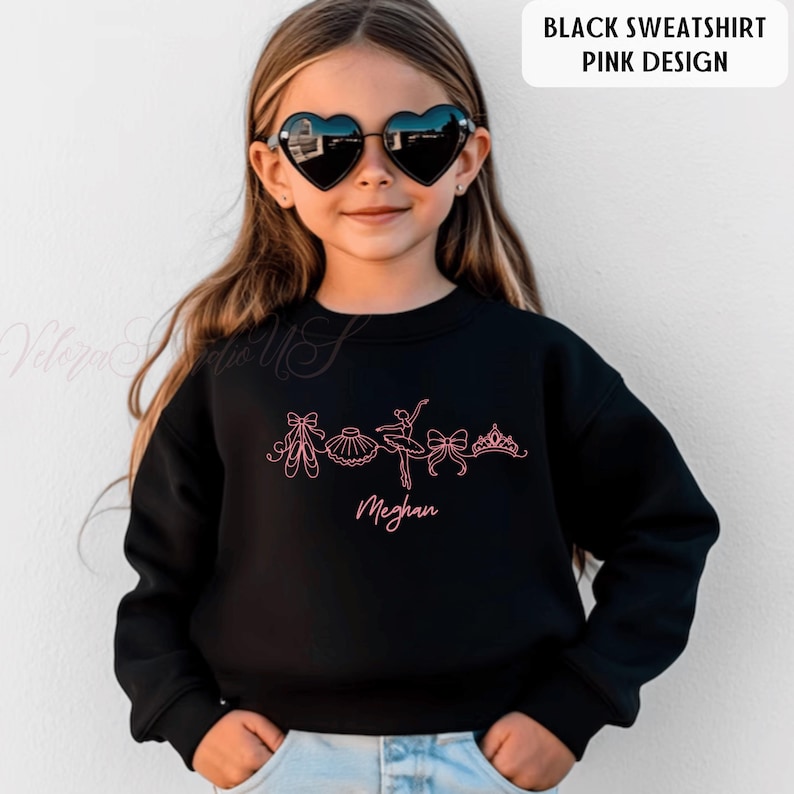 Puede incluir: Sudadera negra con un dise&ntilde;o rosa con tem&aacute;tica de ballet. El dise&ntilde;o incluye zapatillas de ballet, un tut&uacute;, una bailarina, lazos y una tiara. El nombre "Meghan" est&aacute; escrito en rosa debajo del dise&ntilde;o. La esquina superior derecha de la imagen tiene el texto "BLACK SWEATSHIRT PINK DESIGN".
