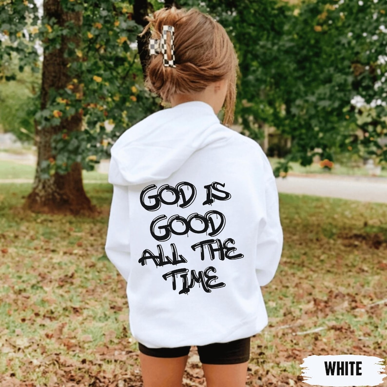 May include: A white hoodie with the text "GOD IS GOOD ALL THE TIME" in black lettering. The hoodie is being worn by a person, with the back of their head and shoulders visible. The word "WHITE" is at the bottom.
