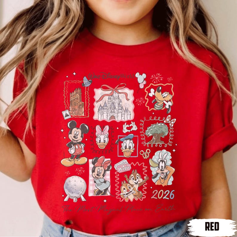 Puede incluir: Camiseta roja con un dise&ntilde;o de Disney. El gr&aacute;fico incluye personajes como Mickey y Minnie Mouse, el Pato Donald y Chip y Chop, junto con el texto "The Most Magical Place on Earth" y el a&ntilde;o "2026".