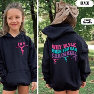 May include: Black youth hoodie with a front pocket and hood. The front features the name "IVY" above a pink gymnast graphic. The back displays the text "WHY WALK WHEN YOU CAN CARTWHEEL" with gymnast figures in pink, teal, and purple.