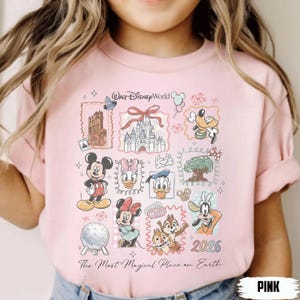 Puede incluir: Camiseta rosa claro con ilustraciones de personajes de Walt Disney World, como Mickey y Minnie Mouse. La camiseta tiene el texto "Walt Disney World" y "The Most Magical Place on Earth". Tambi&eacute;n aparece el a&ntilde;o "2026".