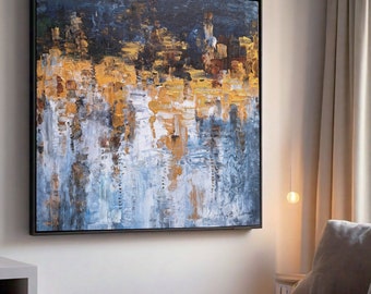May include: Abstract painting with a black frame. The painting features a mix of blue, white, and gold paint in a layered, textured style.