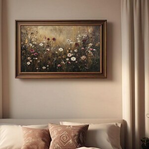 Puede incluir: Una pintura enmarcada de un campo de flores silvestres en tonos de blanco, rosa y morado. El fondo es un dorado suave y apagado.