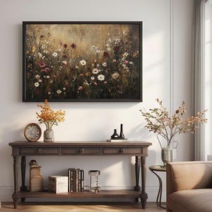 Puede incluir: Una consola de madera marr&oacute;n con tres cajones y un estante inferior. La mesa tiene patas torneadas y est&aacute; decorada con una pintura de un campo de flores silvestres en un marco marr&oacute;n oscuro.