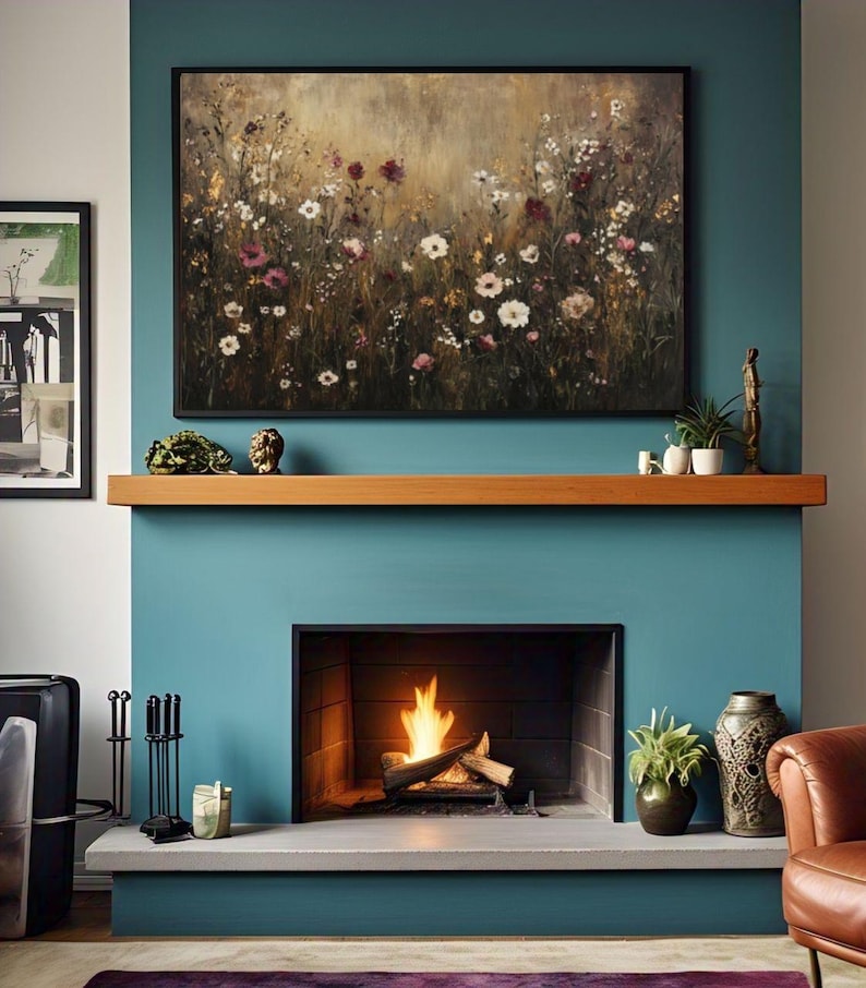 Puede incluir: Una pared azul turquesa con una repisa de madera sobre una chimenea. La chimenea tiene un marco negro y un fuego ardiendo en su interior. Un cuadro de un campo de flores silvestres cuelga sobre la repisa.