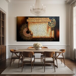May include: Large framed artwork with Arabic calligraphy in gold and brown hues. The artwork is displayed in a dining room setting, above a wooden table with six chairs. A chandelier hangs above the table, and a white rug is on the floor.