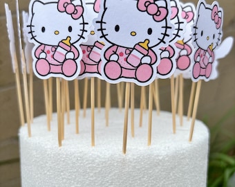 May include: A collection of Hello Kitty cupcake toppers featuring the character in a pink outfit with a matching bow, holding a baby bottle. Each cutout is attached to a thin wooden toothpick, designed for placement into a cake or food item.