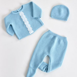 Conjunto de Bebé em  3 peças em Malha e Azul rendado. Leva renda na camisola, uma listra de renda branca desde a gola até ao final da mesma.