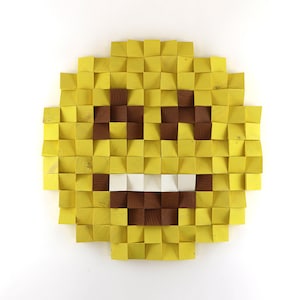 May include: A yellow smiley face made of wooden squares. The eyes and mouth are brown, and the mouth is slightly open in a smile.