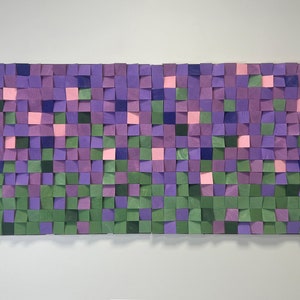 Puede incluir: Una pieza de arte de pared hecha de bloques de madera en tonos de morado, verde y rosa. Los bloques están dispuestos en un patrón de cuadrícula, creando un diseño texturizado y abstracto.