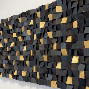 Può includere: Un pannello fonoassorbente a parete in legno. Il pannello è composto da una varietà di forme geometriche, tra cui quadrati, triangoli e rettangoli. Il legno è tinto in tonalità di nero, marrone e oro.