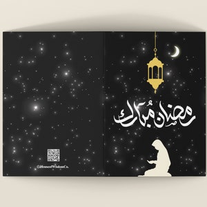 May include: A black card with a white silhouette of a person praying with the Arabic text "Ramadan Mubarak" in gold lettering. A gold lantern hangs from the top of the card with a crescent moon in the background. The card has a black background with white stars.