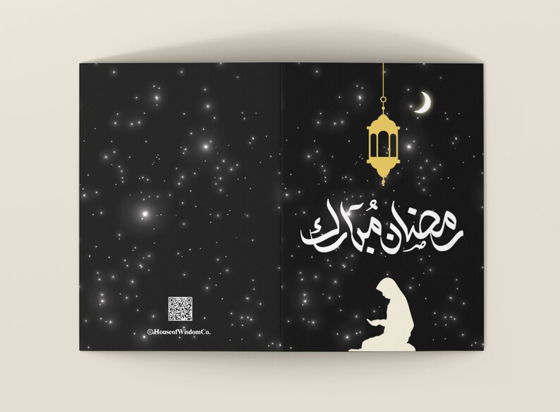 May include: A black card with a white silhouette of a person praying with the Arabic text "Ramadan Mubarak" in gold lettering. A gold lantern hangs from the top of the card with a crescent moon in the background. The card has a black background with white stars.