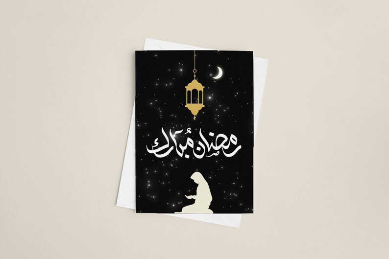 May include: A black card with a white silhouette of a person praying, a gold lantern, and a crescent moon. The card has a white background and the text "Ramadan Mubarak" in Arabic script.