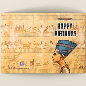 May include: A birthday card with an Egyptian theme. The card features a drawing of an Egyptian queen wearing a blue headdress. The background is a yellow and brown pattern with hieroglyphics. The text "Happy Birthday" is in black letters.