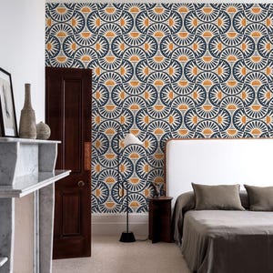 May include: Wallpaper featuring a repeating geometric pattern of dark blue and mustard yellow semicircles and fan shapes. The design covers the wall behind a bed with a white headboard, a dark wood door, and a floor lamp with a white conical shade.