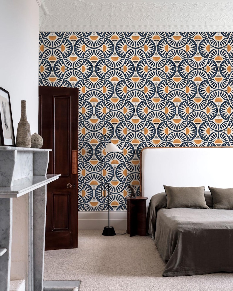 May include: Wallpaper featuring a repeating geometric pattern of dark blue and mustard yellow semicircles and fan shapes. The design covers the wall behind a bed with a white headboard, a dark wood door, and a floor lamp with a white conical shade.