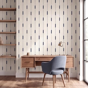May include: Wallpaper featuring a repeating pattern of vertical dark blue lines with small, elongated oval accents on a cream-colored background. The design covers the wall behind a wooden desk with a gray chair and a small desk lamp.
