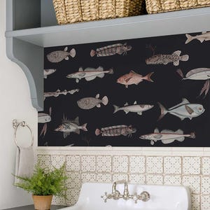 Könnte beinhalten: Ein Badezimmer mit schwarzer Tapete, die verschiedene Fischillustrationen in Grau-, Rosa- und Brauntönen zeigt. Der Raum umfasst ein weißes Waschbecken, einen Topffarn und Weidenkörbe auf einem Regal.