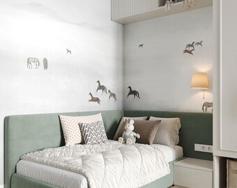 May include: A child's bedroom with a sage green bed and a white comforter. The wall is decorated with horse decals. Decorative pillows and a stuffed bunny are on the bed. A small nightstand and a lamp are next to the bed. A shelf above the bed holds decorative items.