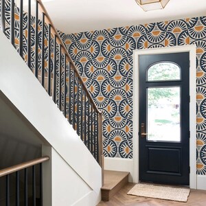 May include: An entryway featuring a dark blue door with a glass panel, a staircase with black metal railings and wooden handrails, and walls covered in wallpaper with a repeating navy blue and mustard yellow fan-shaped geometric pattern.