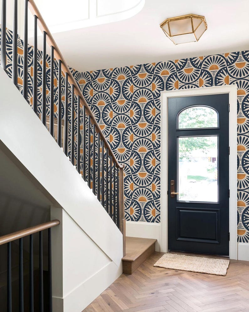 May include: An entryway featuring a dark blue door with a glass panel, a staircase with black metal railings and wooden handrails, and walls covered in wallpaper with a repeating navy blue and mustard yellow fan-shaped geometric pattern.
