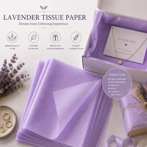 May include: A stack of light purple lavender tissue paper sheets next to an open white gift box containing a thank you card and a gold necklace. A small box wrapped in the same tissue paper with twine and a tag sits nearby with lavender sprigs.