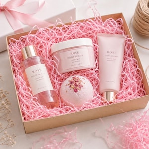 Peut inclure: Un coffret cadeau contenant des produits de bain à la rose nichés dans de la fibre de papier rose. L'ensemble comprend un gel douche de 100 ml, un gommage corporel de 100 ml, une crème pour les mains de 75 ml et une bombe de bain ronde.