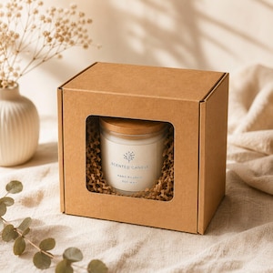 Könnte beinhalten: Eine Duftkerze aus Sojawachs im Glas mit Holzdeckel, verpackt in einem braunen Karton mit quadratischem Sichtfenster. Das weiße Etikett auf der Kerze zeigt eine kleine botanische Illustration und den Text Scented Candle Hand-Poured Soy Wax.