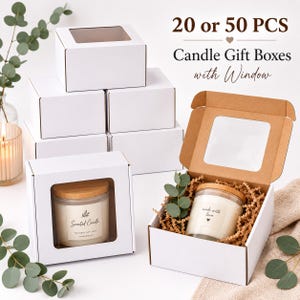 Puede incluir: Cajas de regalo de cartón blanco con ventanas de plástico transparente, disponibles en juegos de 20 o 50 unidades. Las cajas tienen tapa abatible y contienen velas de vidrio con tapas de madera, sobre un lecho de papel kraft triturado.