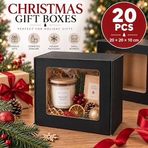 Può includere: Una scatola regalo rettangolare nera con finestra trasparente contenente una candela Winter Spice, una crema mani, una fetta d'arancia essiccata, un rametto di pino e un ornamento dorato. Il testo sulla scatola riporta 20 PCS e 20 x 20 x 10 cm.